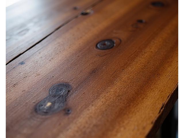 Close-up of a live-edge wooden dining table, showcasing natural wood grain.